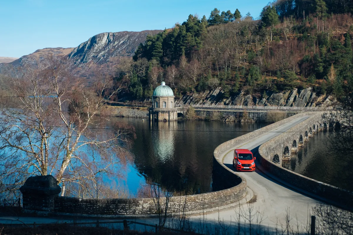 A red MS-RT transit driving over a bridge on a lake